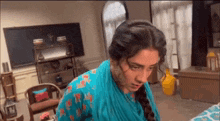 a woman in a blue dress is standing in a living room looking at the camera .