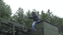 a man standing on top of a military vehicle with trees in the background and the word po on it