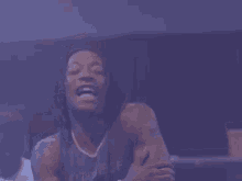 a man with dreadlocks is laughing in a dark room with purple lights .