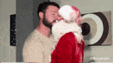 a man in a santa suit is kissing another man