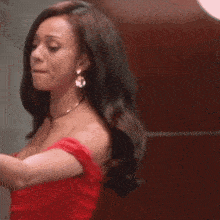 a woman in a red off the shoulder dress and earrings
