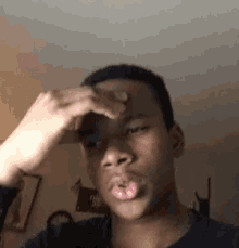 a young man is holding his hand to his forehead while making a funny face .