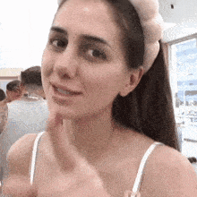 a woman wearing a pink headband is smiling and giving a thumbs up sign