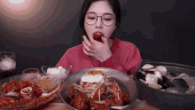a woman with glasses is eating a fried egg on top of a plate of food