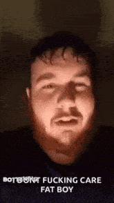 a man with a beard is making a funny face while talking to the camera .