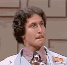 a man in a doctor 's coat and tie is making a face .
