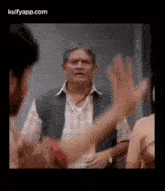 a man is talking to a woman while another man holds his hand up .