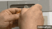 a close up of a person 's hands holding a piece of wood .