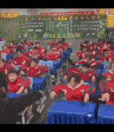 a large group of children are sitting at their desks in front of a chalkboard with chinese writing on it