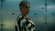 a woman in a leopard print shirt stands in front of a wall