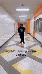a man standing in a hallway with the words ughh i 'm having such a bad day on the floor