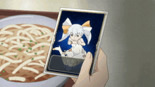 a person is holding a picture of a girl in front of a bowl of soup
