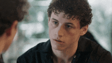 a young man with curly hair has a tattoo on his forehead that says 2020