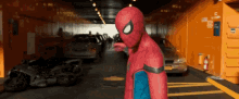 a man in a spiderman costume stands in a parking garage