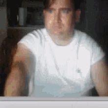 a man in a white shirt is sitting in front of a computer monitor