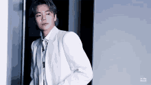 a man in a white suit is standing in a doorway .