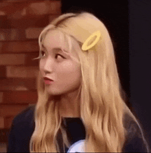 a woman with blonde hair and a yellow hair clip in her hair .