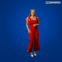 a woman in a red jumpsuit flexes her muscles in front of a blue background that says fox deportes on it
