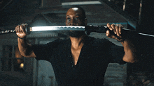 a man in a black shirt is holding a large sword