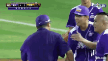 a group of baseball players are shaking hands with a man wearing a purple hat that says tips