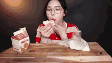 a woman is eating a sandwich next to a carton of milk that says ' korean ' on it