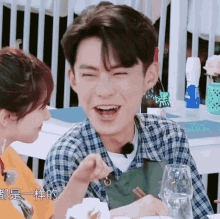 a man wearing a plaid shirt is laughing with a woman
