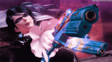 a video game character is holding a blue gun in her hand .