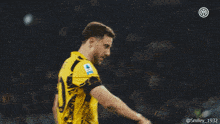 a soccer player wearing a yellow and black jersey with a smiley 1932 logo in the corner
