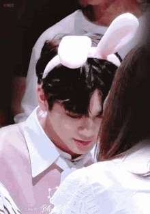 a boy wearing bunny ears is being kissed by a girl .