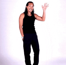 a man in a black tank top and black pants waves his hand