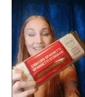 a woman is holding a box of spaghetti in her hands .
