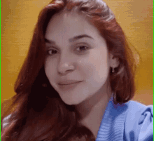 a woman with long red hair is wearing a blue sweater