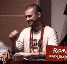 a man is sitting at a table with a red sign that says roma aka bad