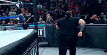 a man in a black shirt stands in a wrestling ring with a sign that says " it "
