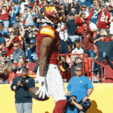 a football player holds a ball in front of a crowd with the number 22 on his shirt