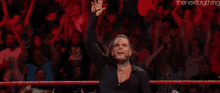 a man is standing in front of a crowd with his hand up in the air .