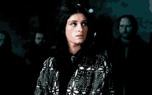 a woman wearing a black and white jacket is standing in a dark room .