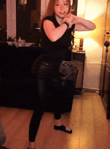a woman in a black shirt and black pants is dancing
