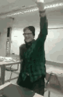 a man in a green sweater is raising his arm in the air .