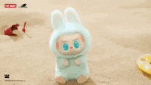a stuffed animal in a bunny costume is sitting on a sandy beach .