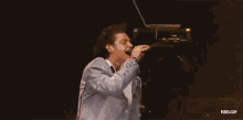a man singing into a microphone with a yellow light behind him and the words rbd.gif below him