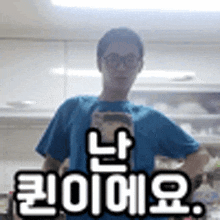 a man in a blue shirt and glasses is taking a selfie in a kitchen with a cell phone .