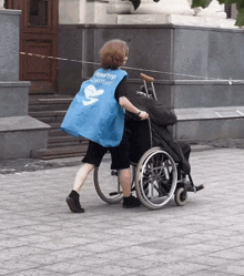a woman wearing a blue vest that says volunteer pushes a wheelchair