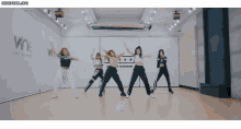 a group of girls are dancing in front of a wall that says t number