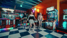 three girls are dancing in an arcade with a basketball arcade game in the background