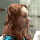 a woman with red hair is looking at herself in a mirror