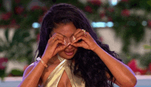 a woman is covering her eyes with her hands while wearing a gold top .