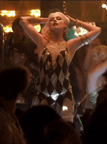 a woman in a harlequin dress is dancing in a crowded room