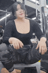 a woman is squatting on a bench in a gym .