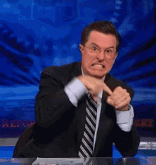 a man in a suit and tie is making a funny face while sitting at a desk